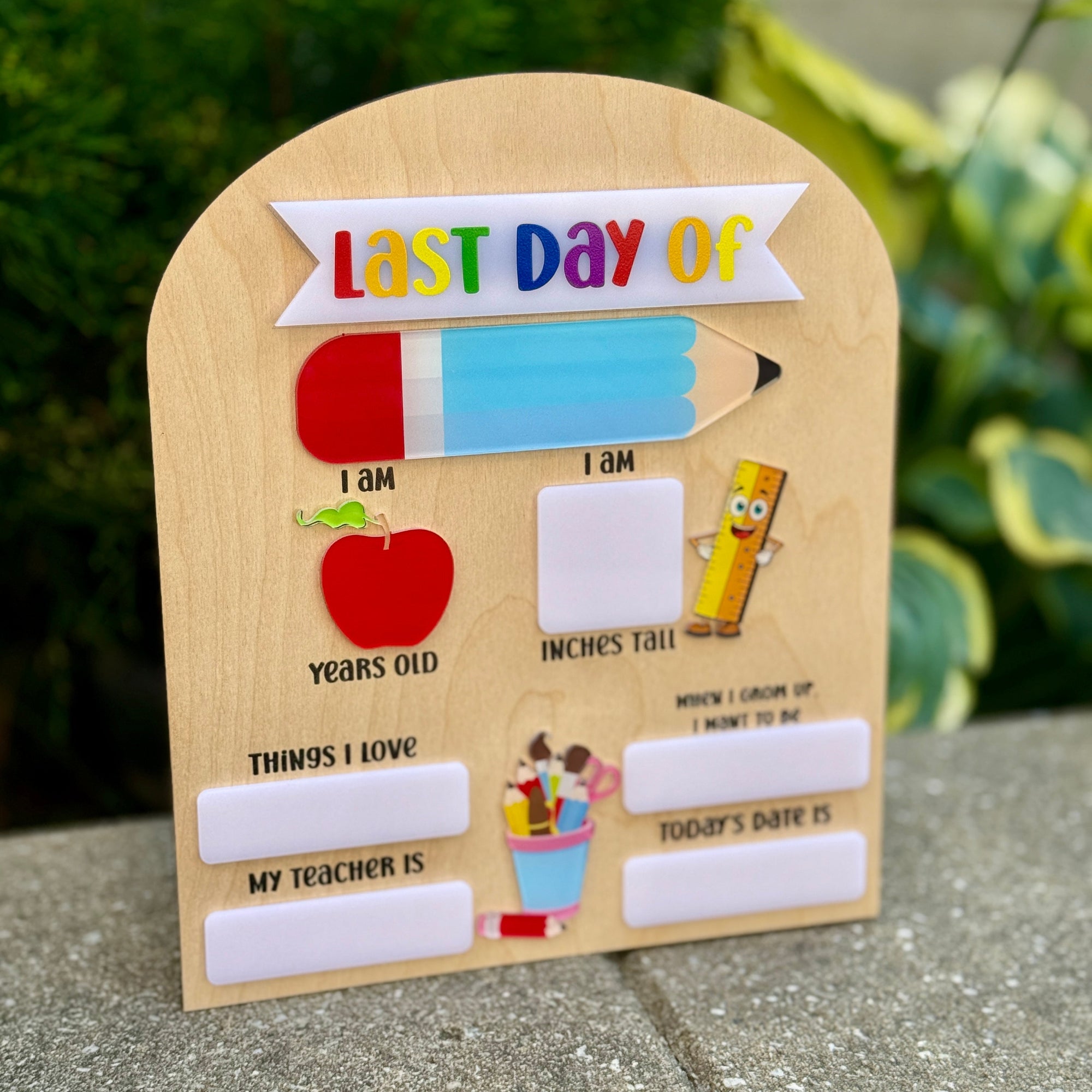 Wooden plaque with 'Last Day of' text and educational graphics on a concrete surface.