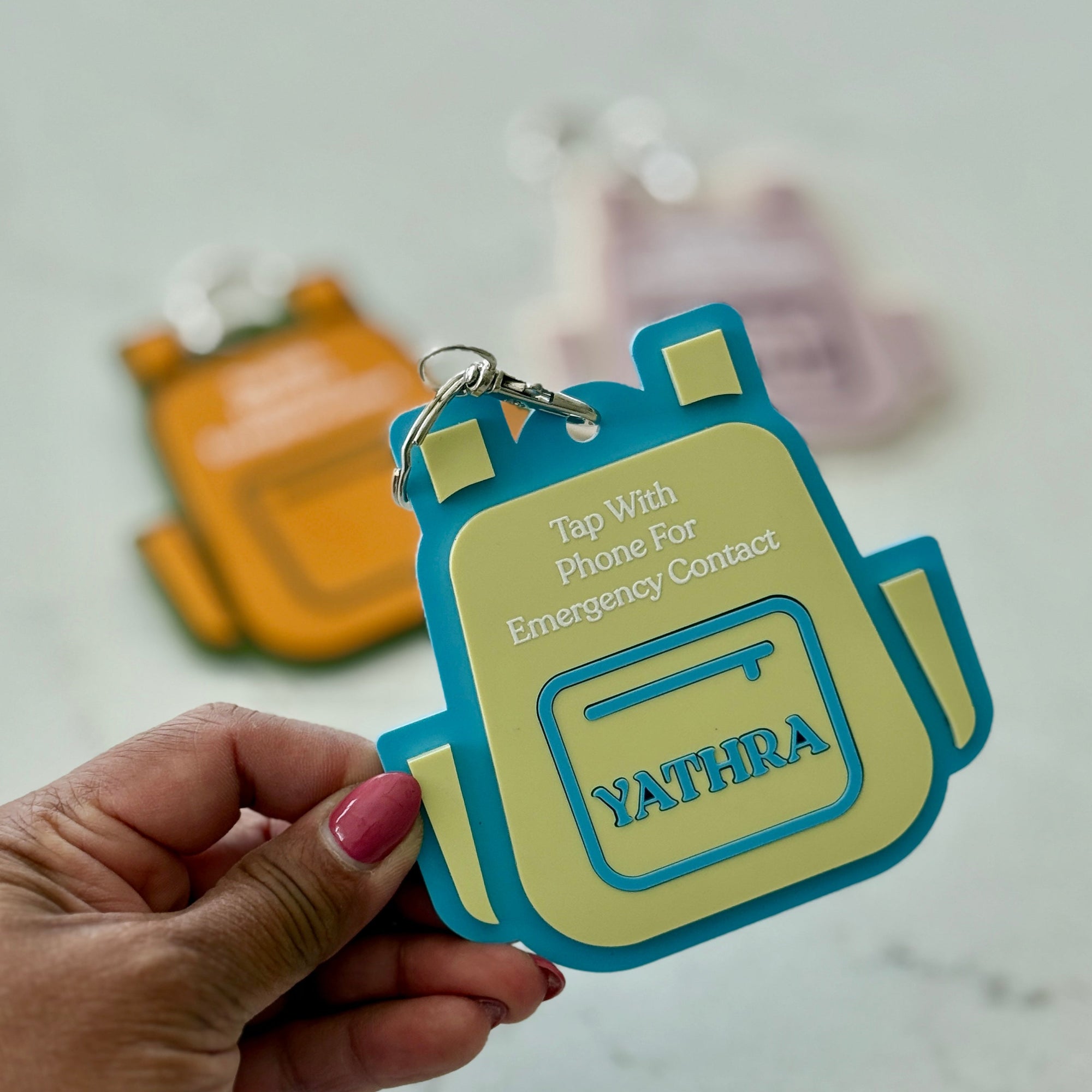 Hand holding a colorful keychain with 'YATHRA' branding on a light gray background