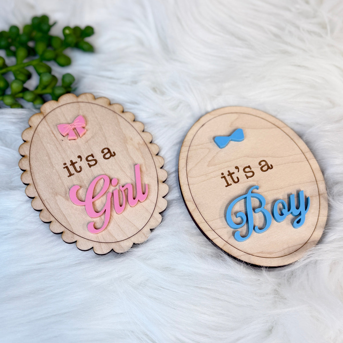 Two wooden signs indicating 'it's a Girl' and 'it's a Boy' on a textured white surface.