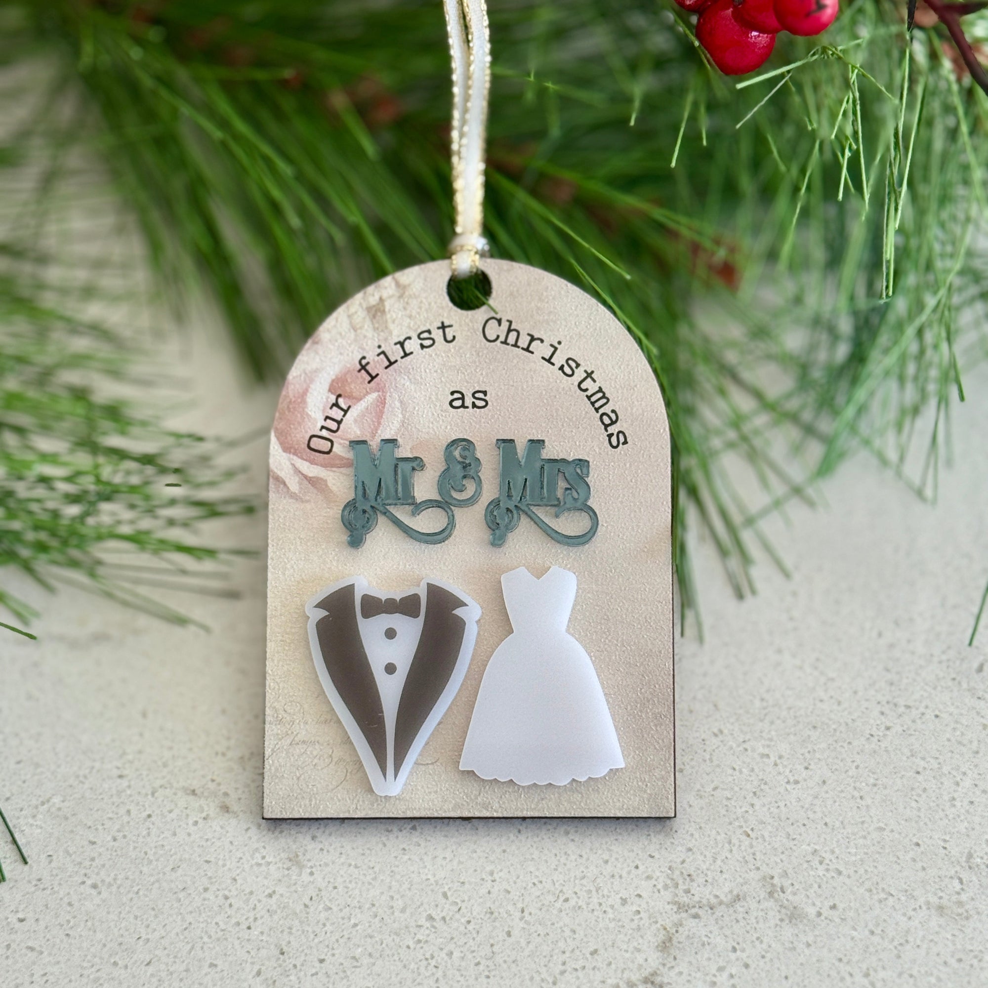 Decorative Christmas ornament with 'Mr & Mrs' and wedding attire cutouts, hanging on a branch.
