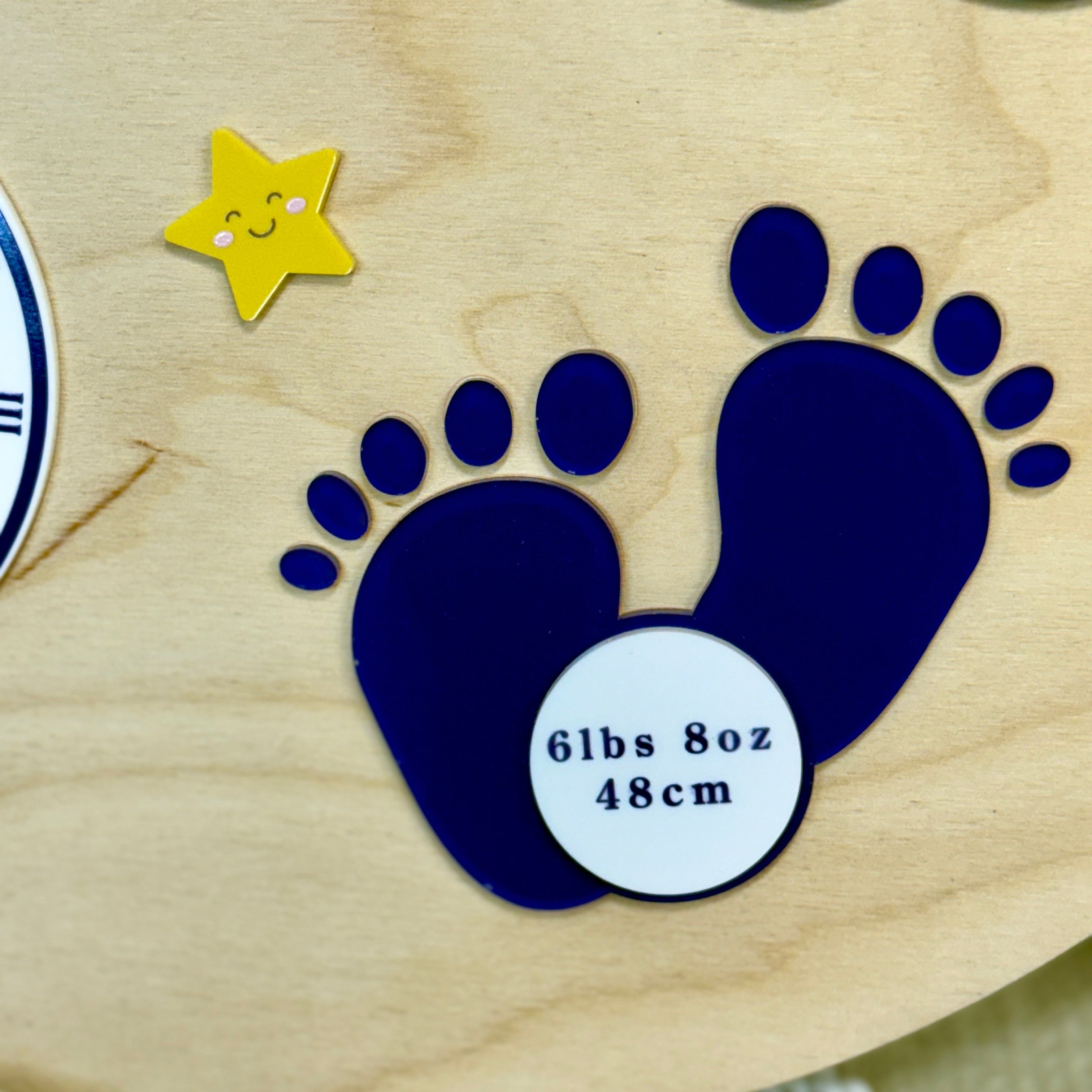 Wooden plaque with blue baby footprints and weight measurement on a wooden background
