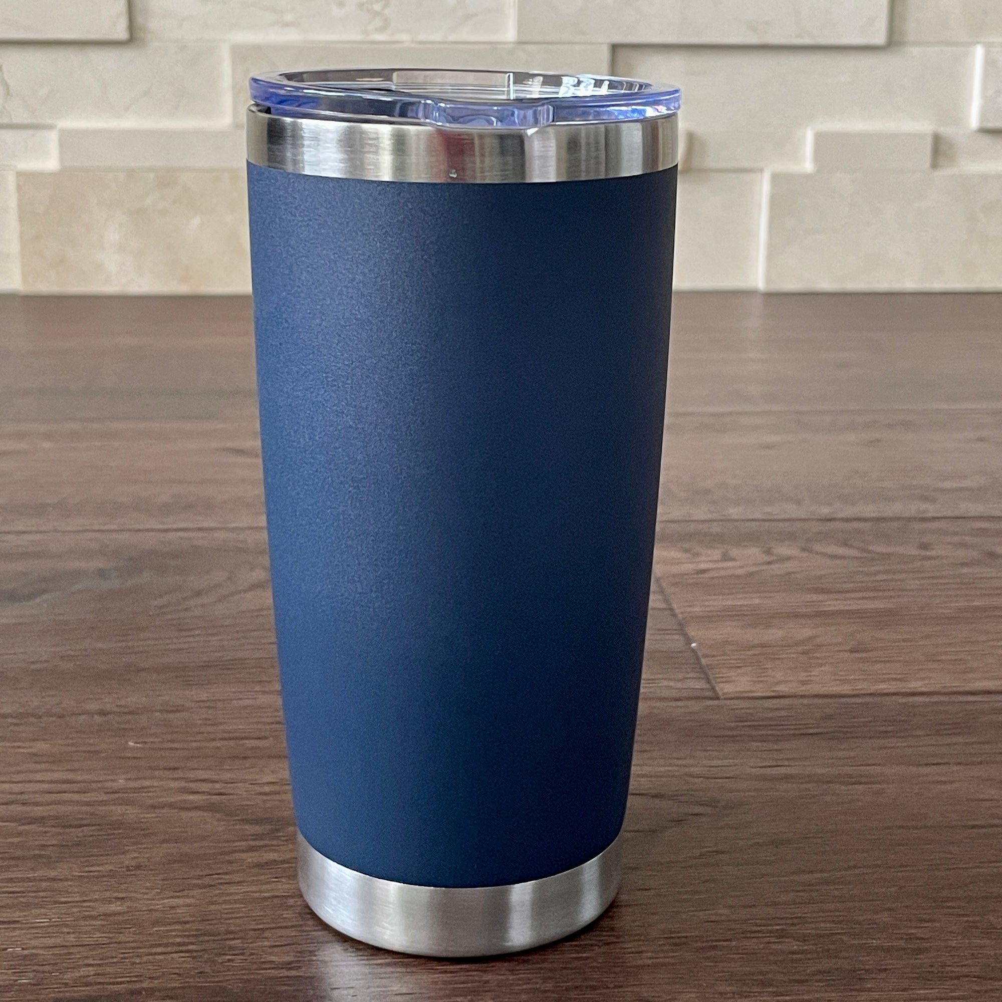 Navy Blue insulated tumbler with silver base and lid on a wooden surface.
