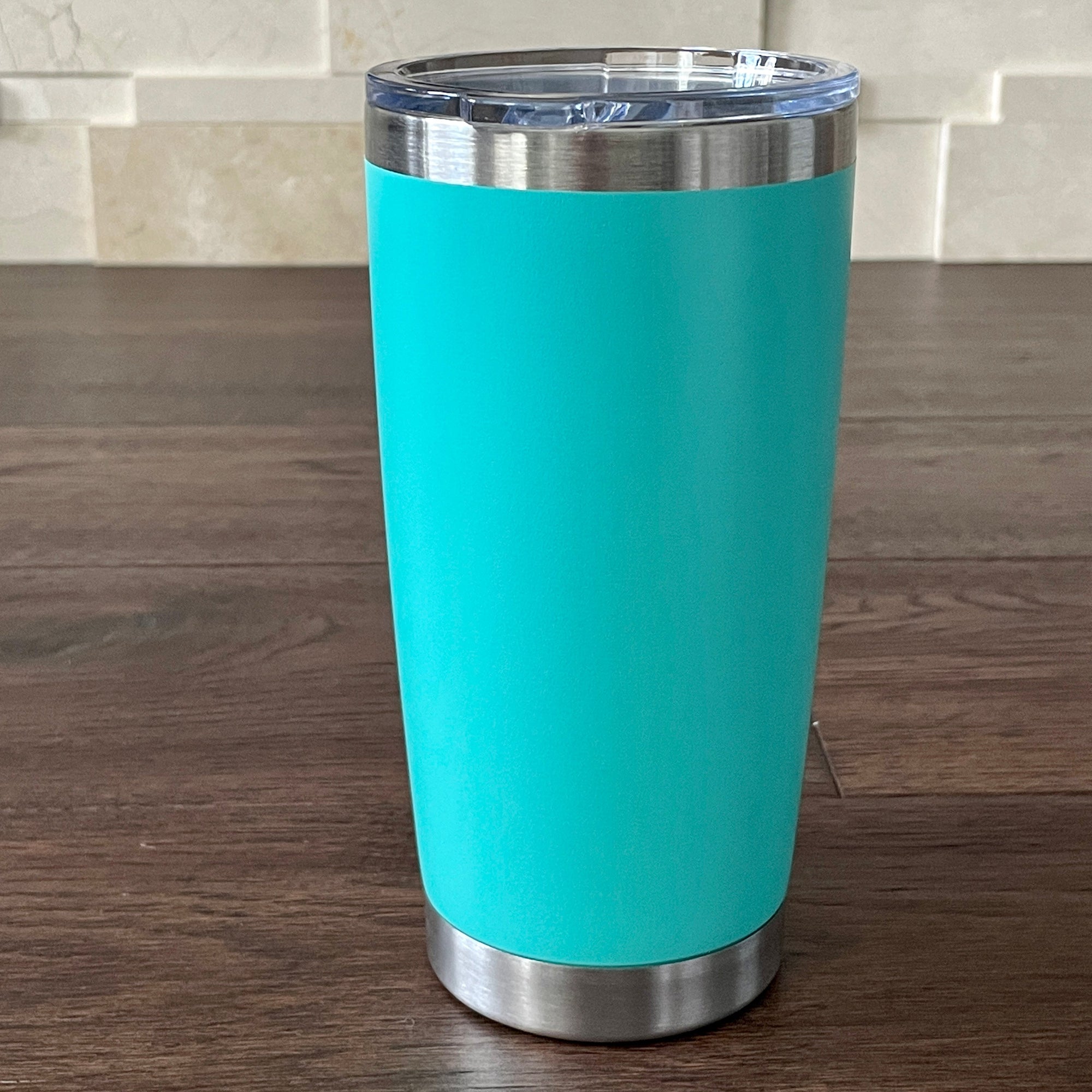 Teal Blue tumbler with silver base and rim on a wooden surface.