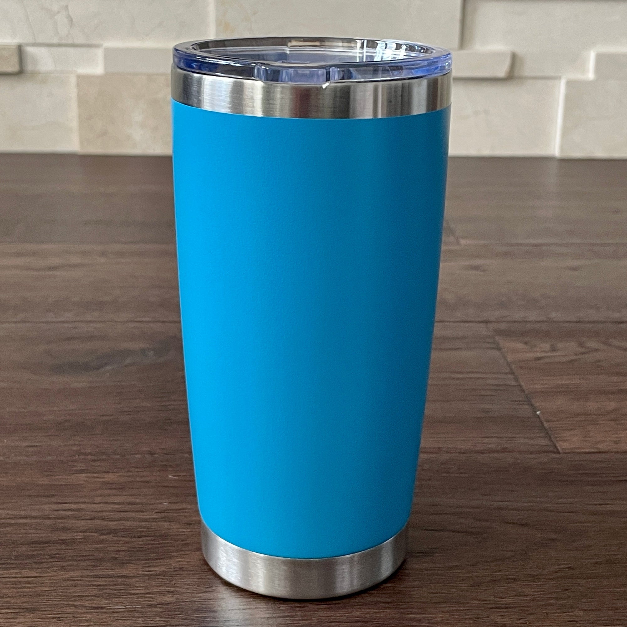 Lake Blue insulated tumbler with silver base and rim on a wooden surface.