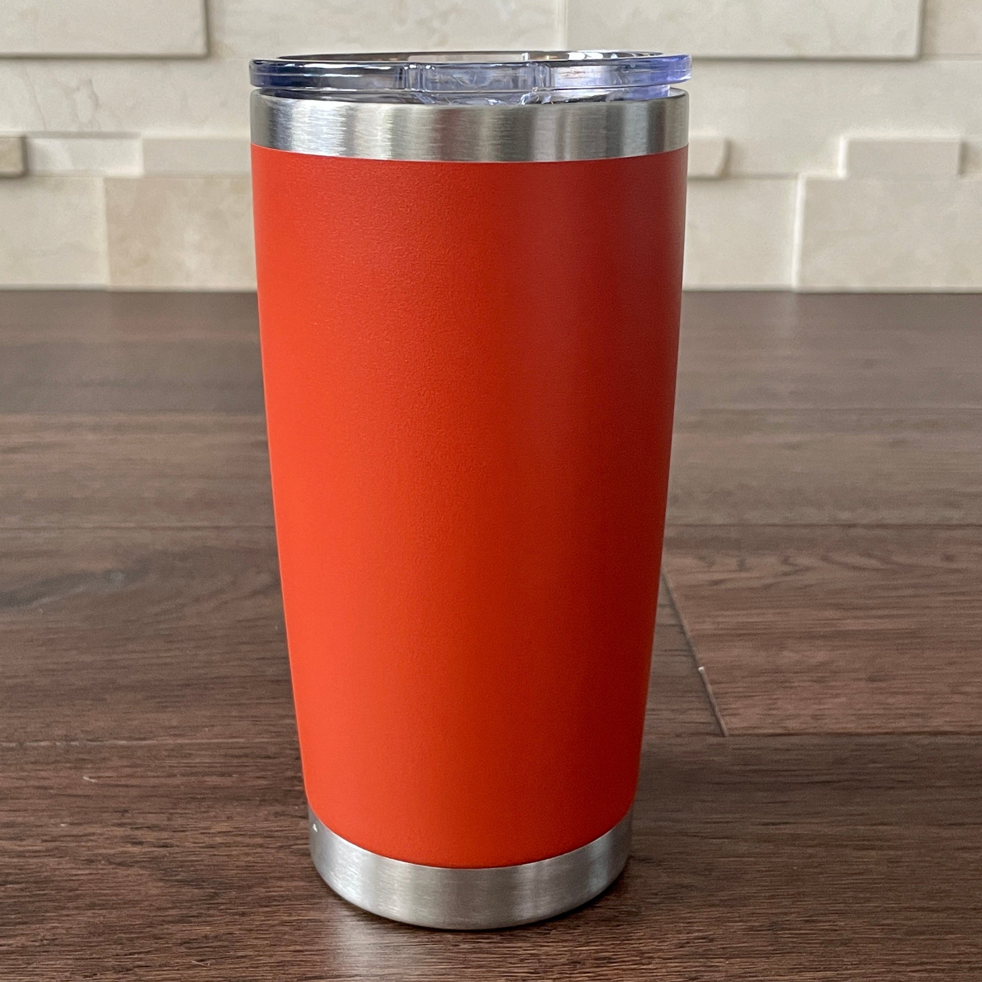 Burnt Orange tumbler with silver rim on a wooden surface