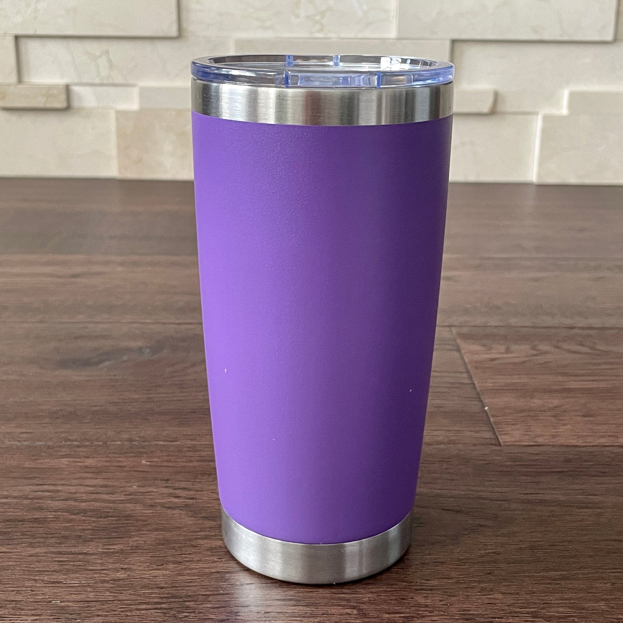 Purple tumbler with silver rim on a wooden surface