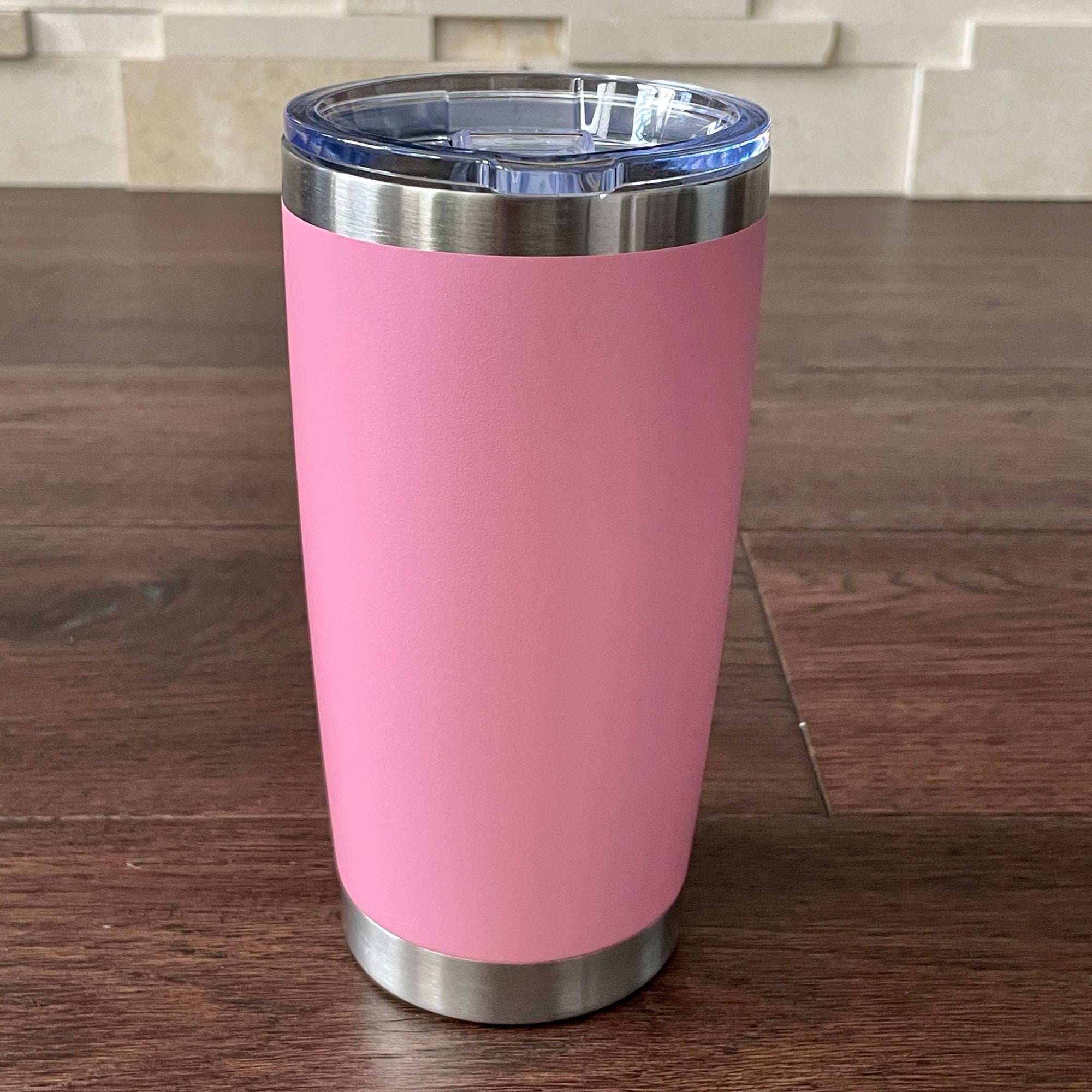 Light Pink tumbler with a silver base and lid on a wooden surface.
