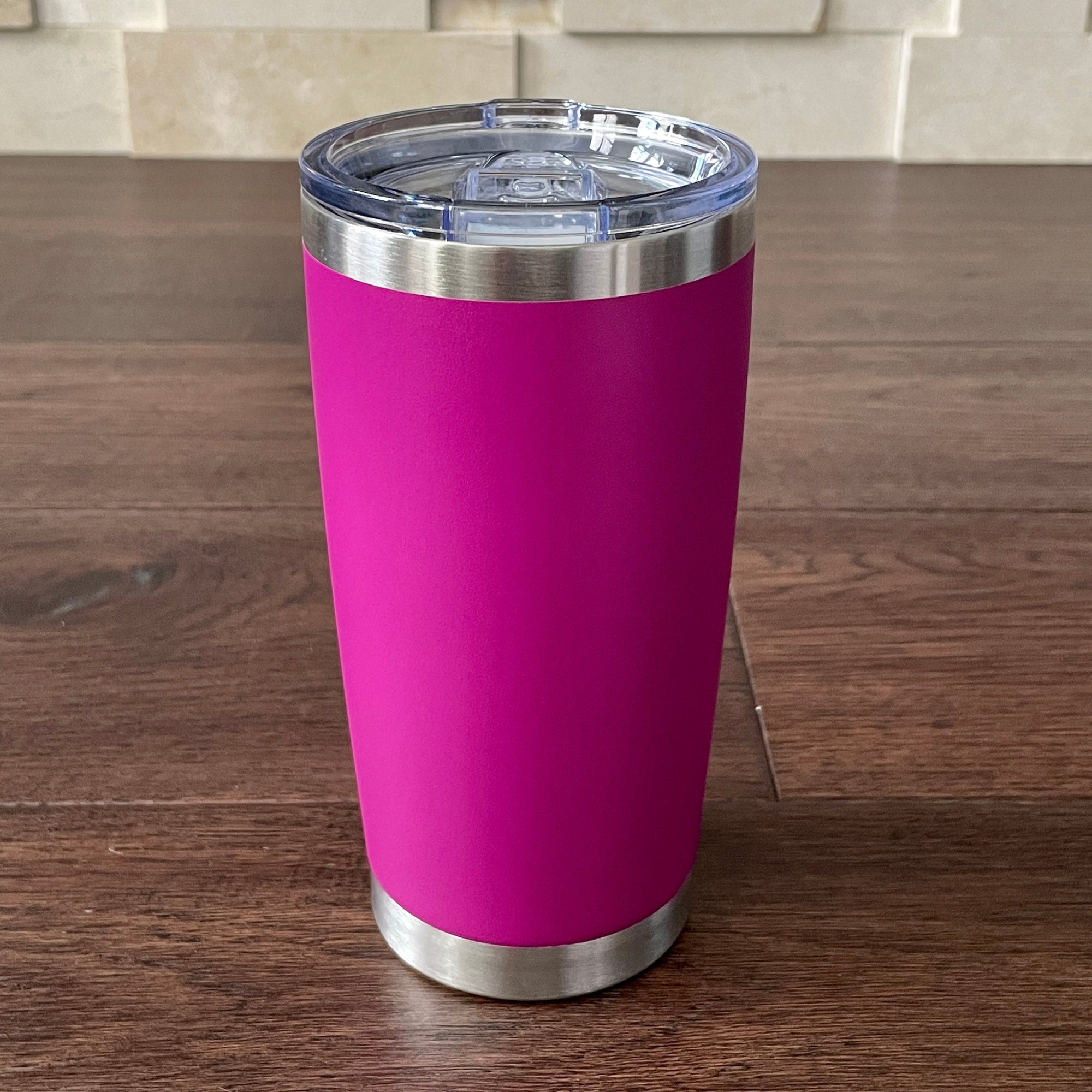Magenta tumbler with a silver base and lid on a wooden surface.