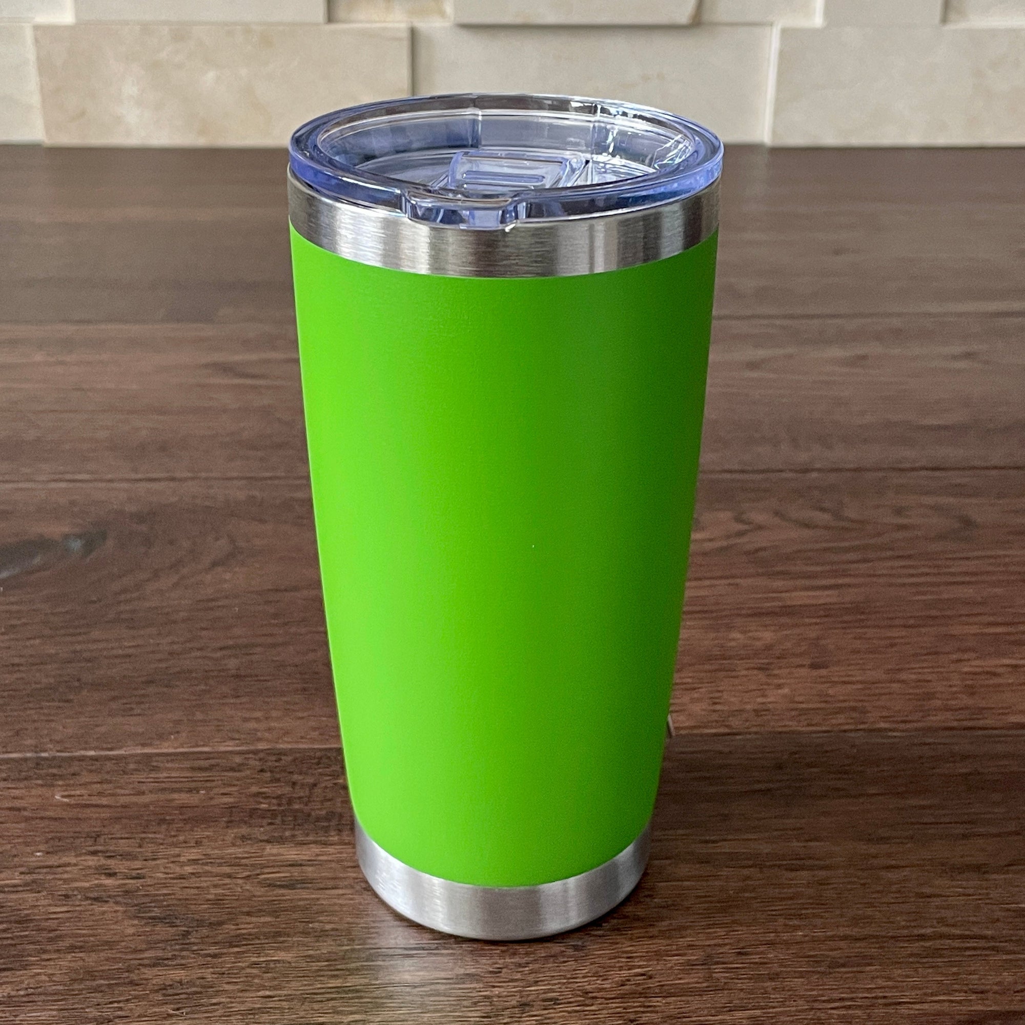 Light Green tumbler with silver base and blue lid on a wooden surface.