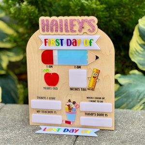 Children's first day of school sign with a wooden frame on a stone surface.