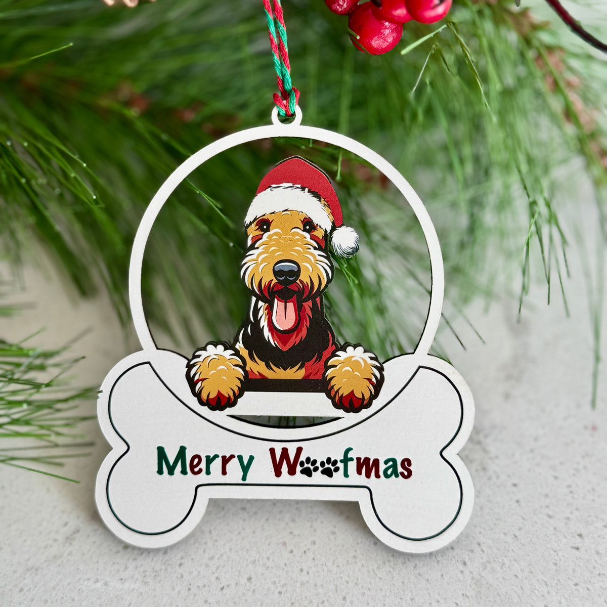 Christmas ornament with a dog wearing a Santa hat and 'Merry Woofmas' text, hanging on a tree.