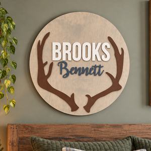 Personalized round wooden deer antler nursery name sign featuring raised name.