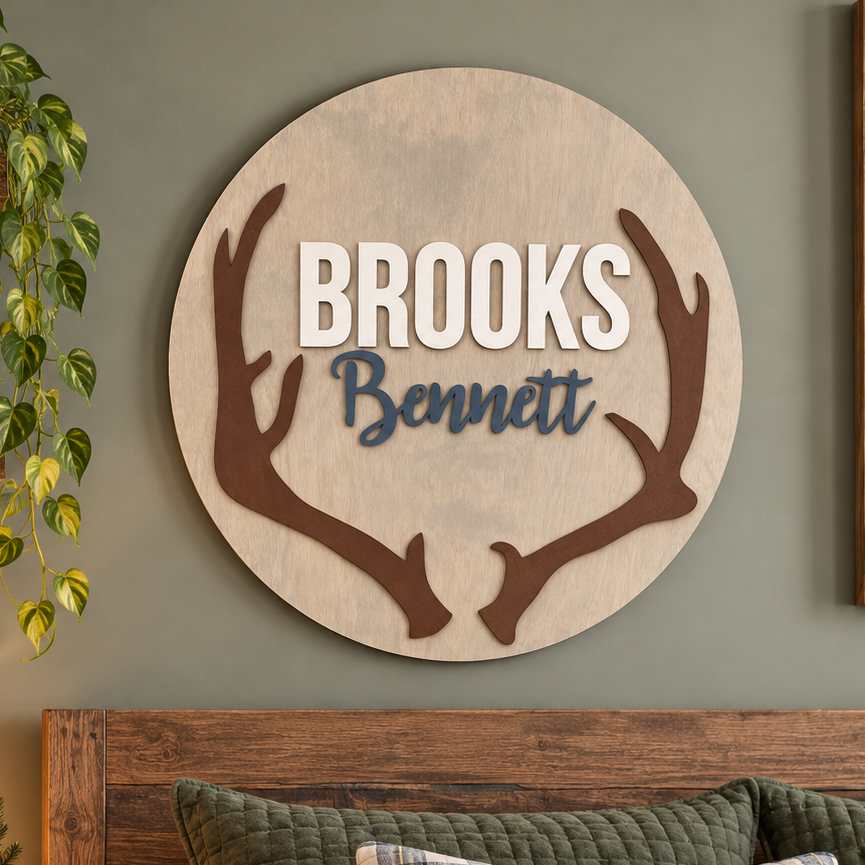 Personalized round wooden deer antler nursery name sign featuring raised name.