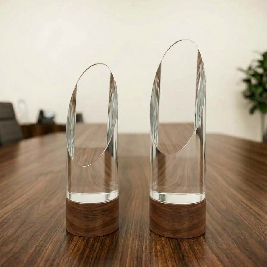 Clear crystal oval arch corporate award with a dark wood-finish base displayed on a wooden tabletop.