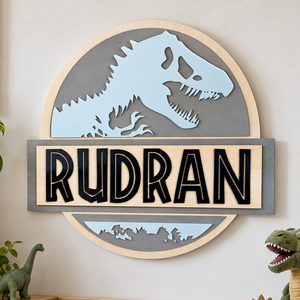 Personalized dinosaur wooden name sign featuring a blue T-Rex silhouette, grey circular backer and black 3D acrylic lettering, displayed on a brick wall.
 Copy