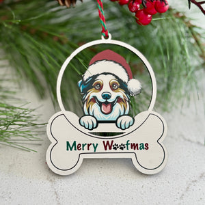 Christmas ornament with a dog wearing a Santa hat and 'Merry Woofmas' text, hanging on a tree.