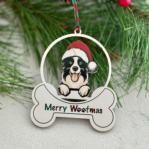 Christmas ornament with a dog wearing a Santa hat and 'Merry Woofmas' text, hanging on a pine branch.