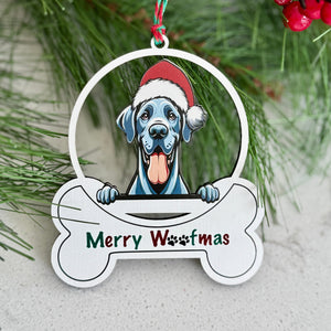 Christmas ornament with a dog wearing a Santa hat and 'Merry Woofmas' text, hanging on a pine branch.