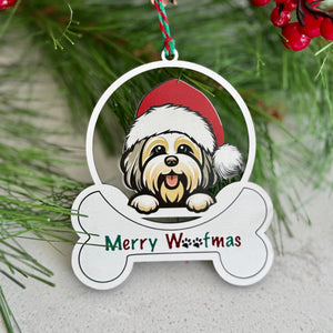 Christmas ornament with a dog wearing a Santa hat and 'Merry Woofmas' text, surrounded by pine branches and red berries.