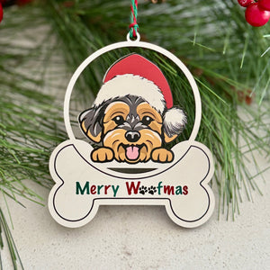 Christmas ornament with a dog wearing a Santa hat and 'Merry Woofmas' text, surrounded by pine branches and red berries.