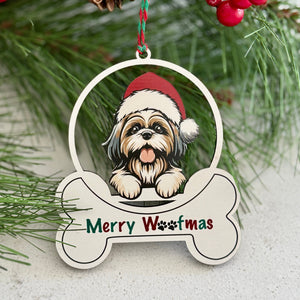 Christmas ornament with a dog wearing a Santa hat and 'Merry Woofmas' text, surrounded by pine branches and berries.