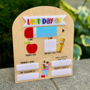 Wooden plaque with 'Last Day of' text and educational graphics on a concrete surface.