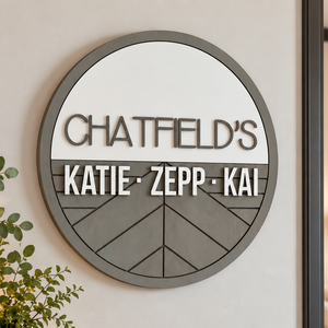 Personalized round wooden nursery name sign featuring names n raised 3D lettering, neutral wood tones and engraved geometric chevron pattern.