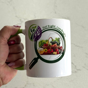 Mug with a 'Eat Right, Live Bright' design featuring a magnifying glass over fruits and vegetables, held by a hand.