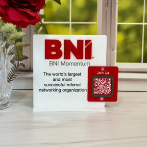 BNI Momentum sign with QR code on a table with flowers and window in the background