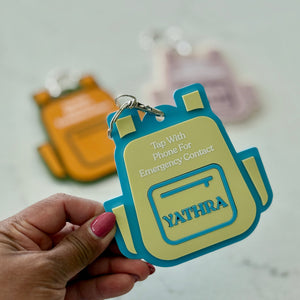 Hand holding a colorful keychain with 'YATHRA' branding on a light gray background