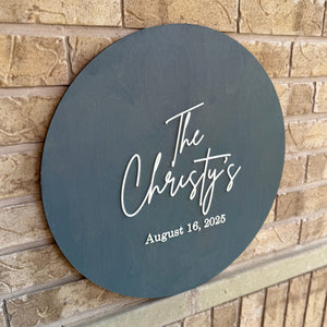Round dark gray sign with 'The Christy's' and date on a brick wall