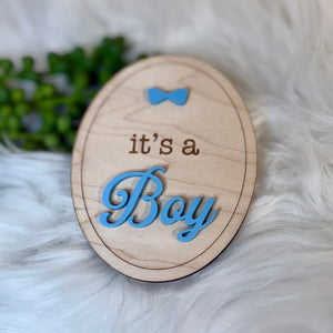 Wooden plaque with 'it's a Boy' text on a fluffy white surface