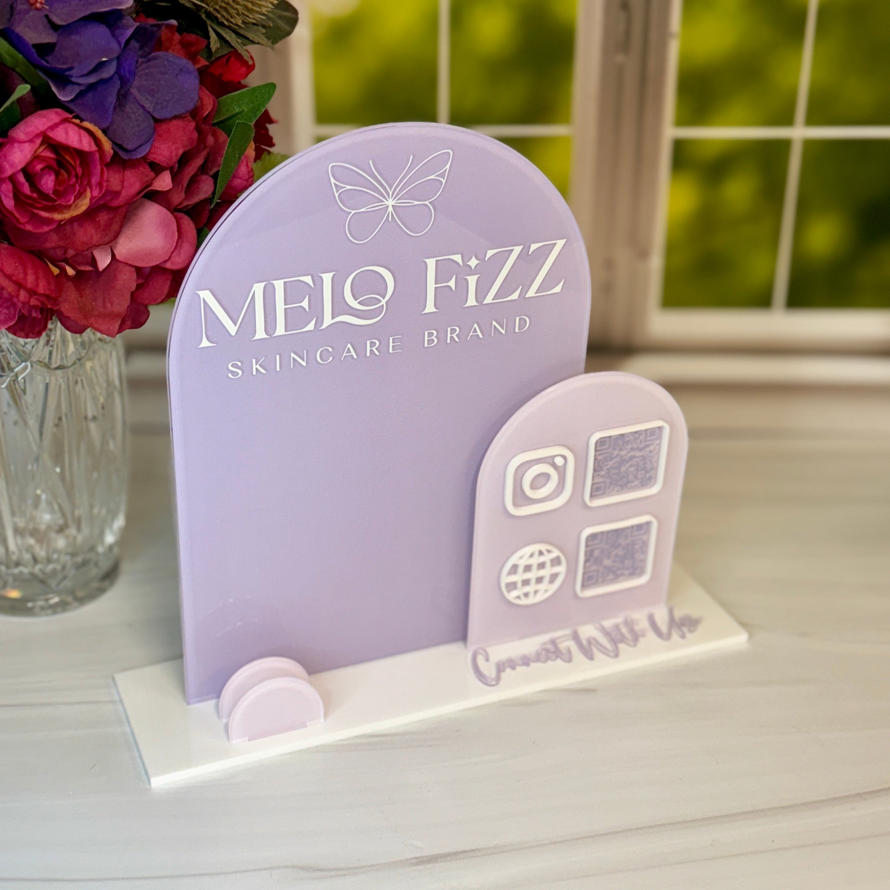 Melo Fizz skincare brand display stand with flowers in the background