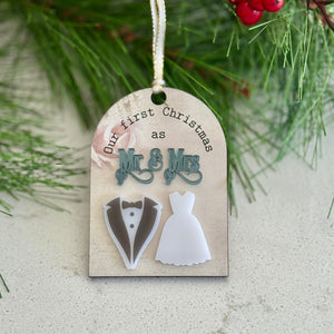 Decorative Christmas ornament with 'Mr & Mrs' and wedding attire cutouts, hanging on a branch.
