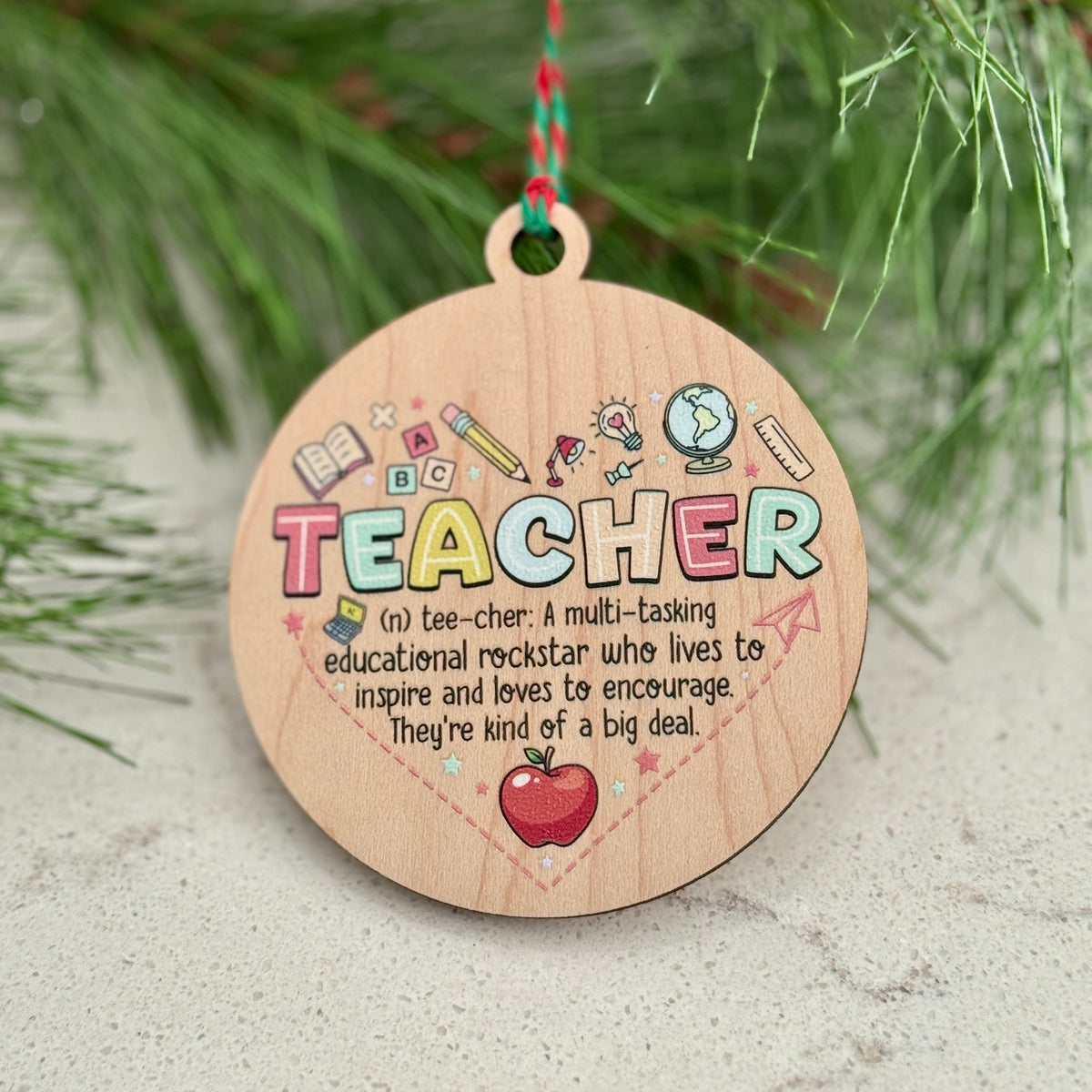 Wooden ornament with colorful text 'I'm a Teacher' on a Christmas tree branch.