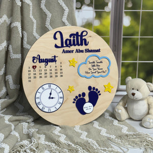 Wooden plaque with baby-themed designs and text, placed on a textured surface with a teddy bear in the background.