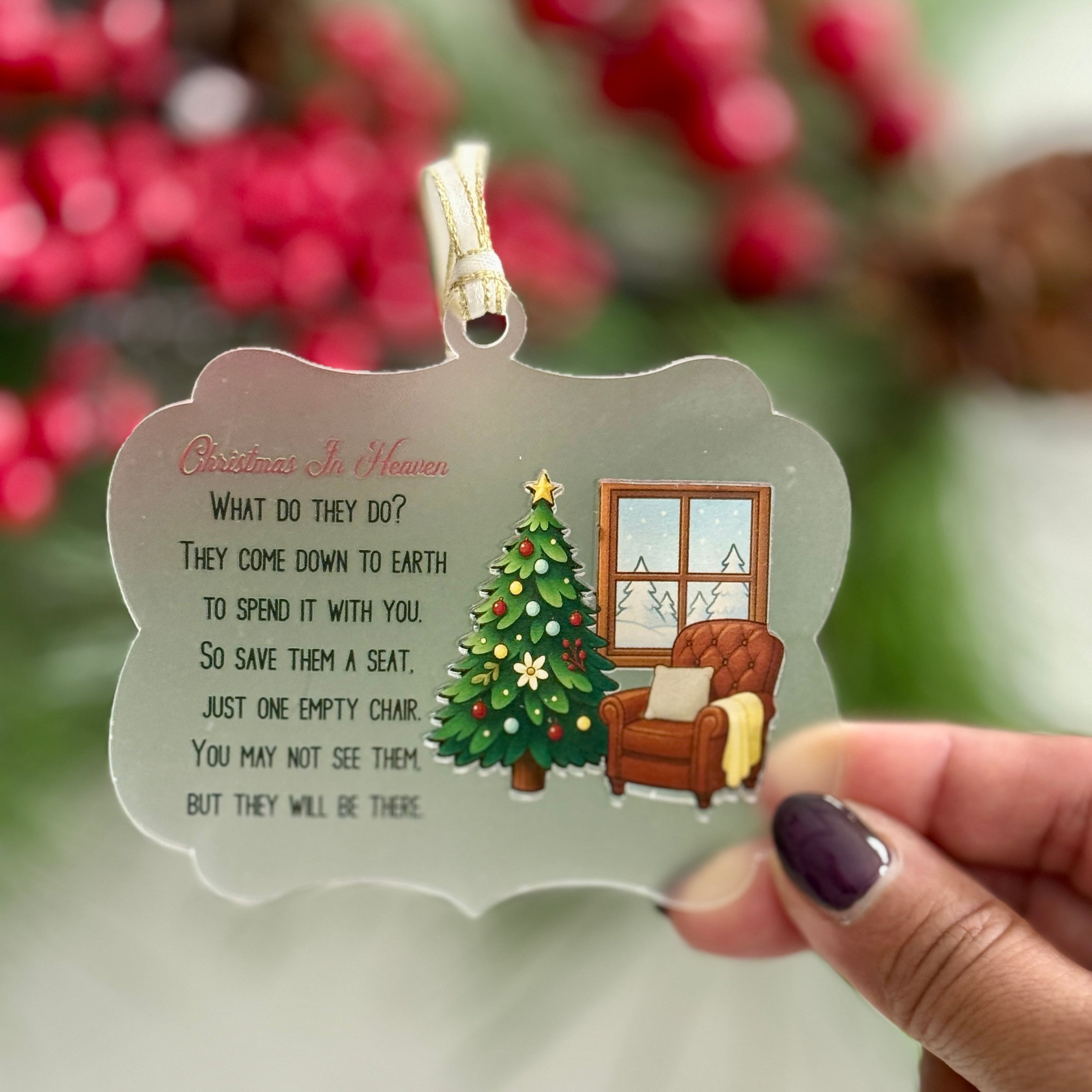 Decorative Christmas ornament with a scene of a tree and chair, held by a hand.