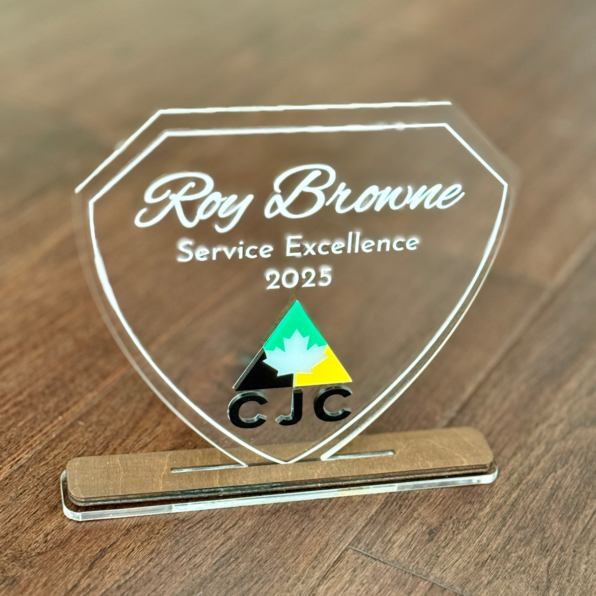 Acrylic award with 'Roy Browne Service Excellence 2025' text on a wooden surface