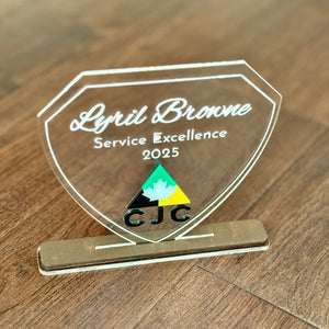A clear award plaque with text and a logo on a wooden surface