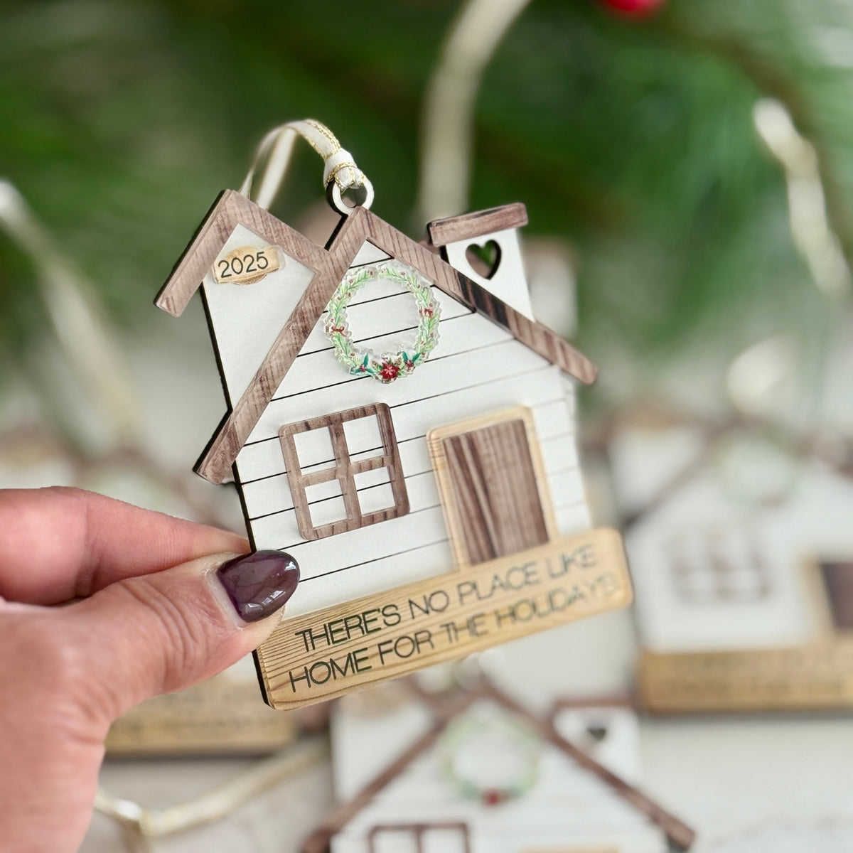 Decorative house ornament with text held by a hand against a blurred background
