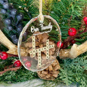 Decorative Christmas ornament with cross and 'Our Family' text on a green leafy background.