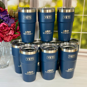 Set of blue YETI tumblers with NPD logo on a white surface with flowers in the background