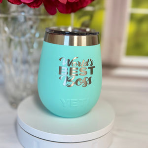 Turquoise wine tumbler with 'Your Best Self' text on a white surface with flowers in the background