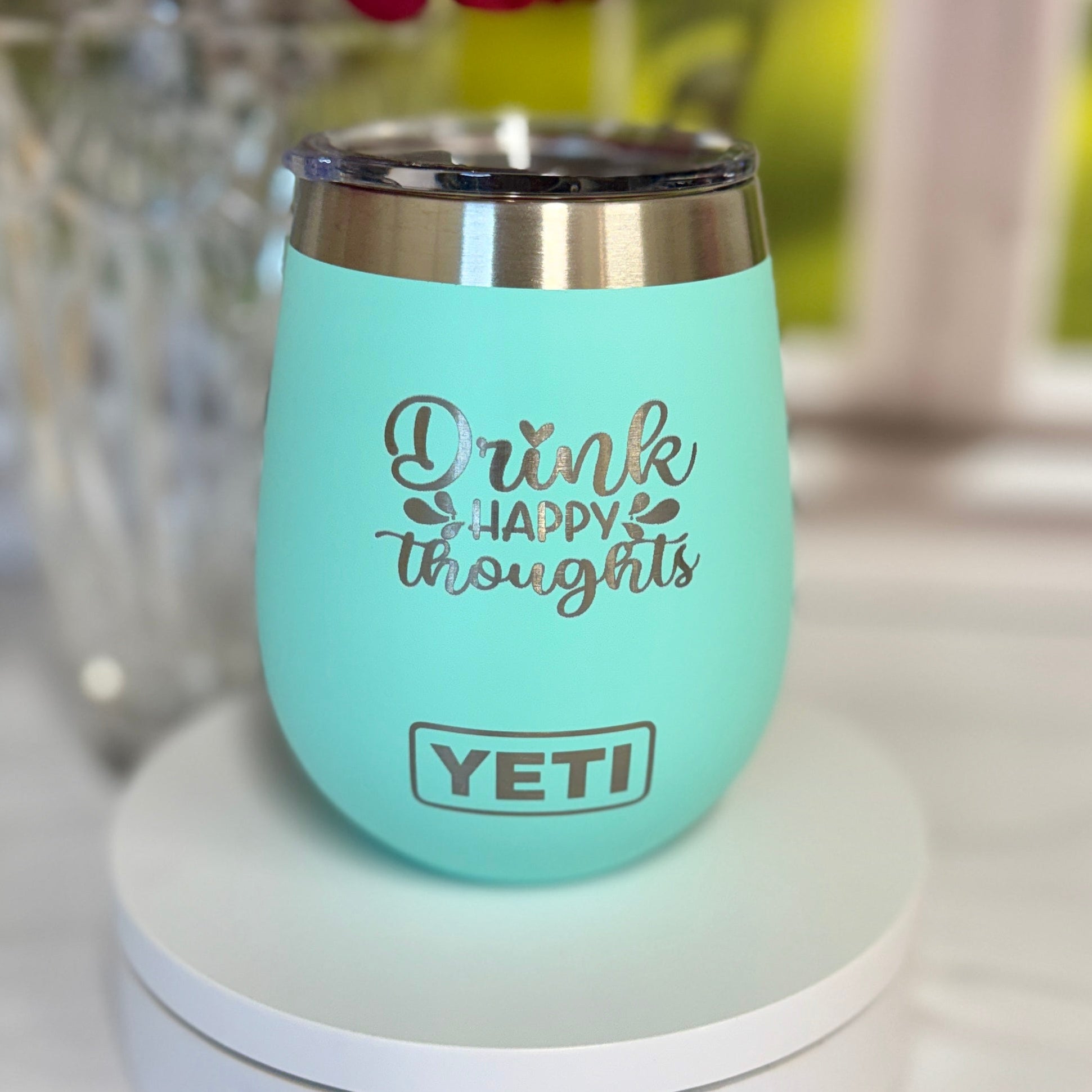 Mint green YETI mug with text on a surface with flowers in the background