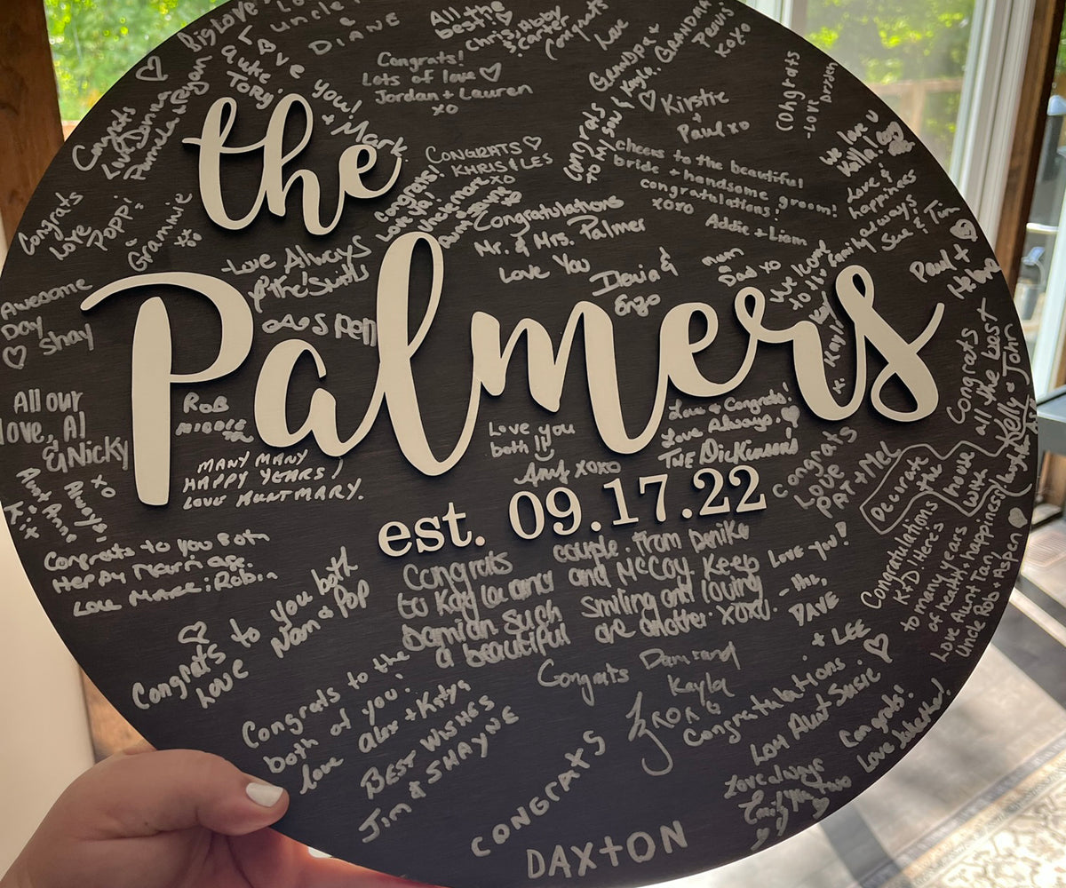 Round sign with family name and established date used for guests to sign at wedding reception